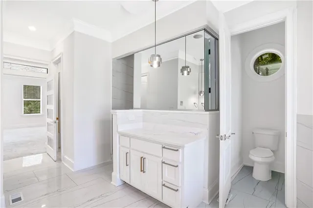 a spacious bathroom with a granite countertop sink a toilet and a shower