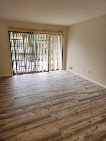 a view of an empty room with wooden floor and a window