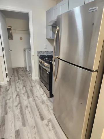 a view of a refrigerator in kitchen and an empty room