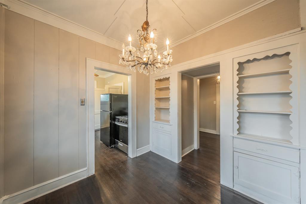 1500 Proctor Avenue Waco, TX 76708 - Photo 18 of 40 The room features dark hardwood flooring and a decorative chandelier, with built-in shelving and cabinets on the right