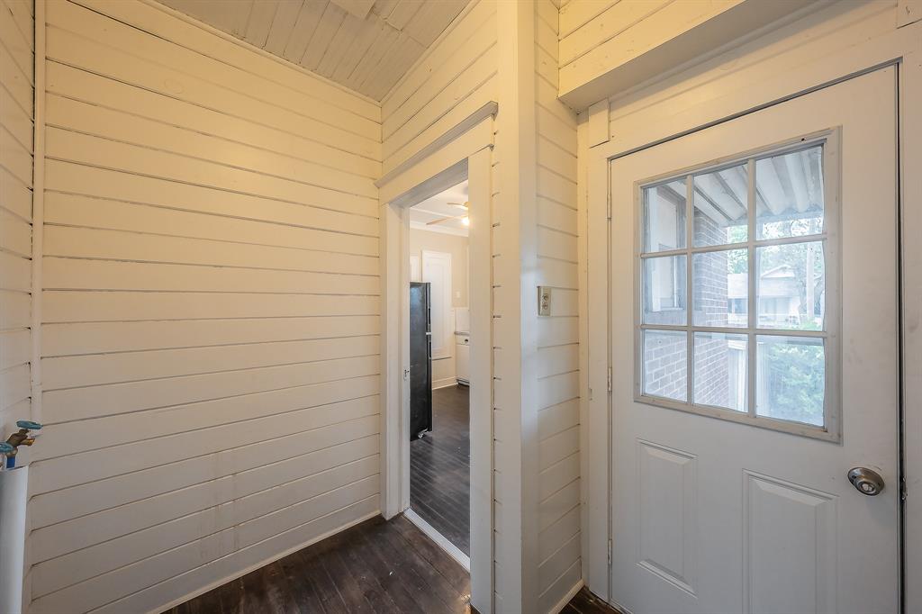 1500 Proctor Avenue Waco, TX 76708 - Photo 26 of 40 This area features white horizontal paneling on the walls and ceiling, dark wood flooring, and a white door with a window offering a view of a brick exterior