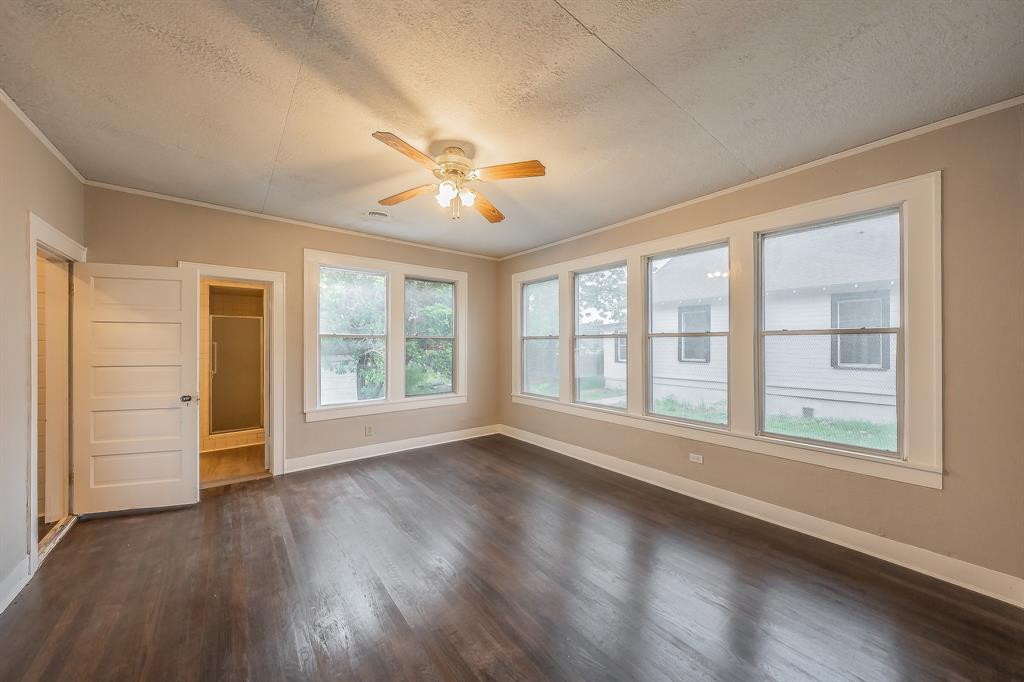 1500 Proctor Avenue Waco, TX 76708 - Photo 30 of 40 Spacious room featuring dark wood flooring, a ceiling fan with light fixture, and a series of large windows providing ample natural light