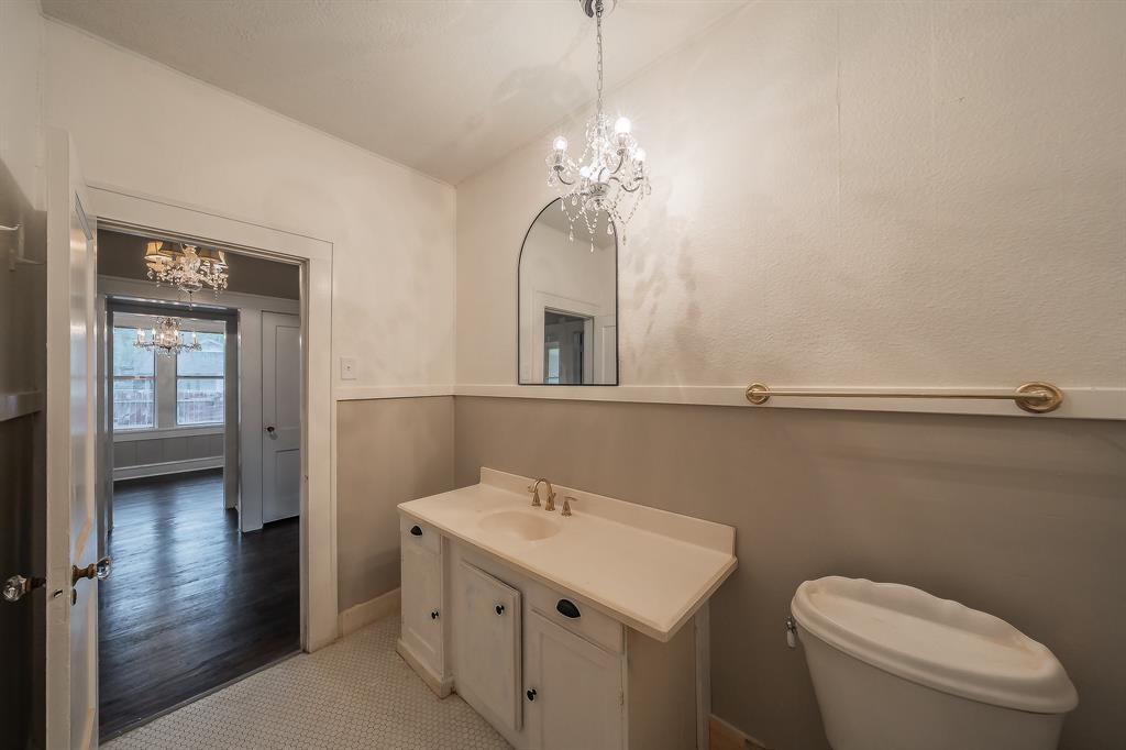 1500 Proctor Avenue Waco, TX 76708 - Photo 36 of 40 The bathroom includes a vanity with a sink, a toilet, a wall-mounted mirror, and a chandelier