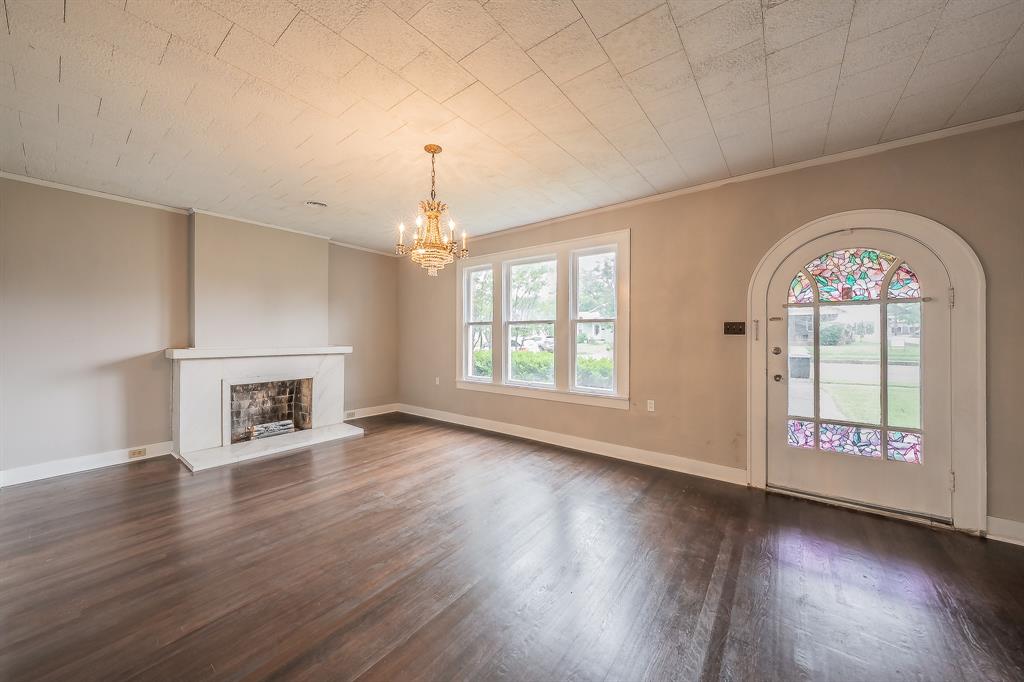 1500 Proctor Avenue Waco, TX 76708 - Photo 7 of 40 This spacious room features dark hardwood flooring, a white fireplace, and a decorative chandelier