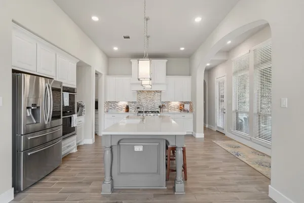 a kitchen with stainless steel appliances white cabinets and a stove top oven
