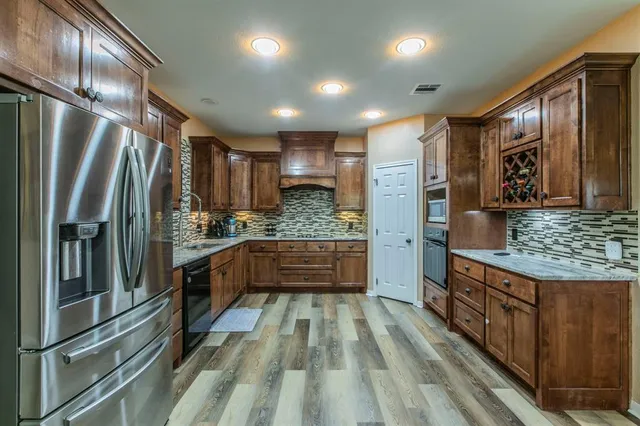 a kitchen with stainless steel appliances granite countertop a refrigerator and a stove top oven