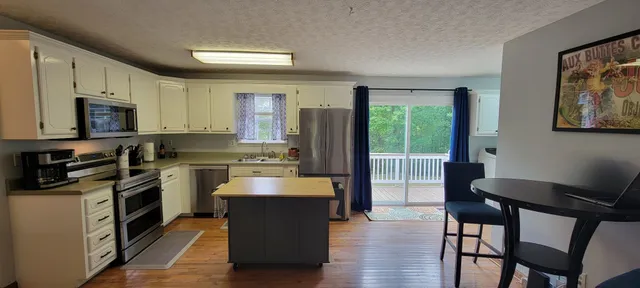 a kitchen with stainless steel appliances granite countertop a stove top oven a sink dishwasher a dining table and chairs with wooden floor