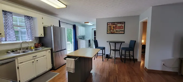 a kitchen with stainless steel appliances a dining table chairs and wooden floor