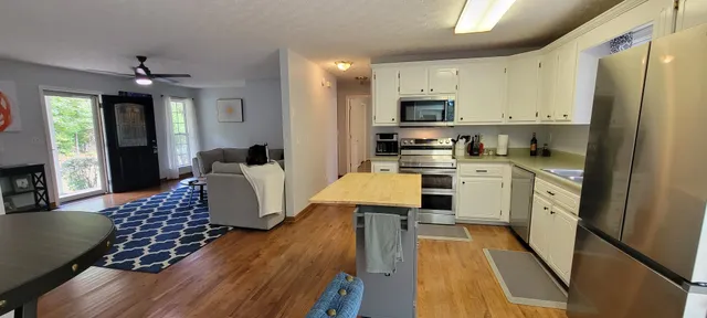 a kitchen with granite countertop a stove top oven a sink dishwasher a dining table and chairs with wooden floor