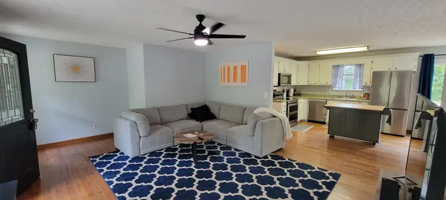 a living room with stainless steel appliances furniture a rug and a window