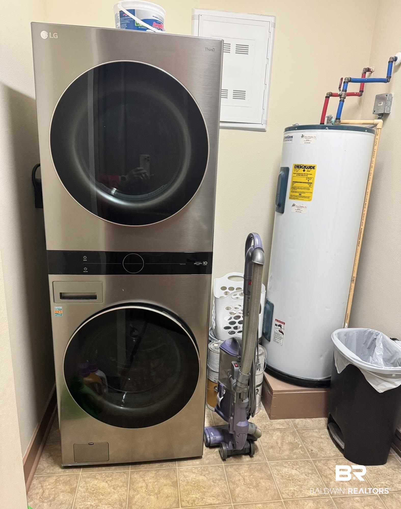 1430 Regency Road, Unit C101 Gulf Shores, AL 36542 - Photo 17 of 32 Laundry room featuring water heater, stacked washing machine and dryer, electric panel, and light tile patterned floors