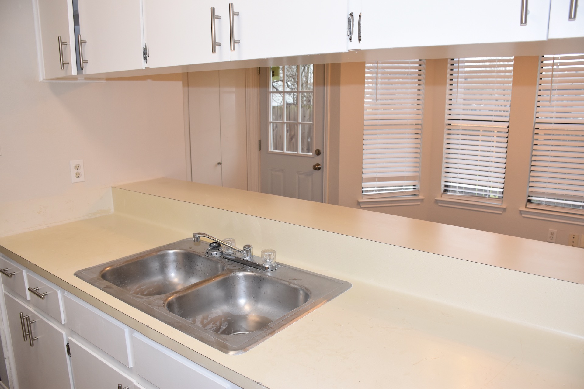 1810 Rawhide Loop Round Rock, TX 78681 - Photo 16 of 29 Kitchen countertop with a double basin stainless steel sink, white cabinetry, and brushed nickel hardware