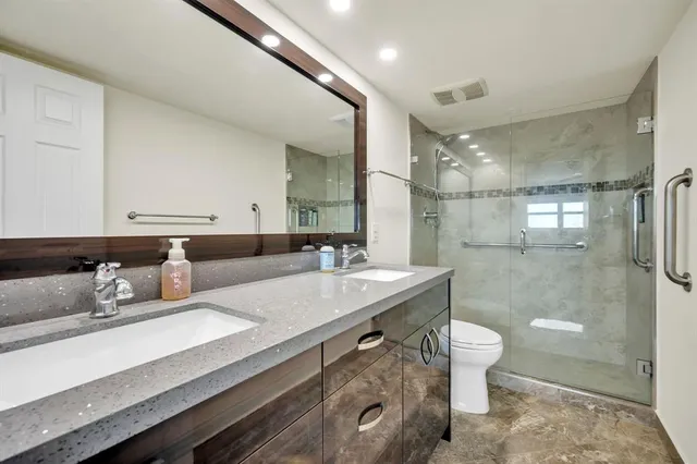 a bathroom with a sink a toilet a mirror and shower