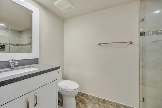 a bathroom with a granite countertop sink mirror vanity and toilet