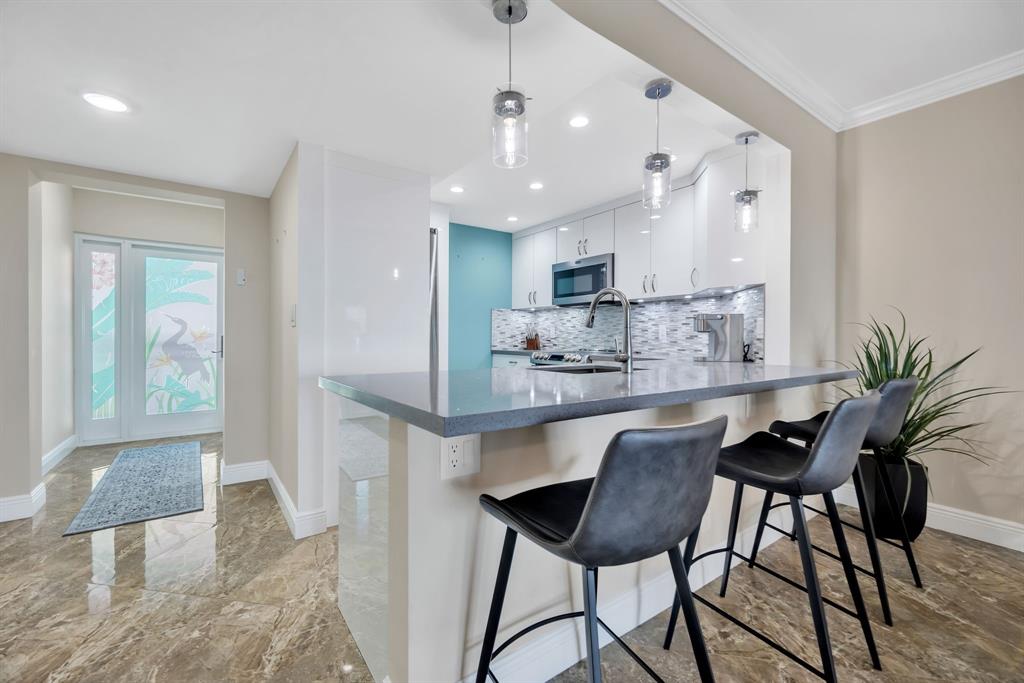 615 North Riverside Drive, Unit 702 Pompano Beach, FL 33062 - Photo 5 of 38 a kitchen with kitchen island granite countertop a table and chairs in it