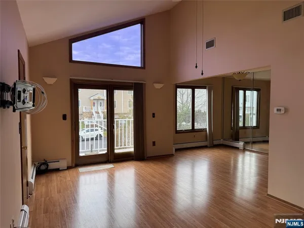 a view of an empty room with window and wooden floor