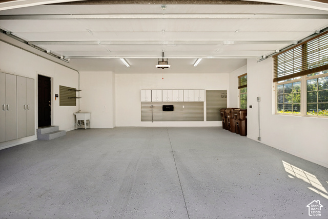 259 Twin River Loop Alpine, UT 84004 - Photo 58 of 61 Expansive garage with durable epoxy flooring, multiple windows featuring wood-finish blinds, abundant white cabinetry, and a utility sink.