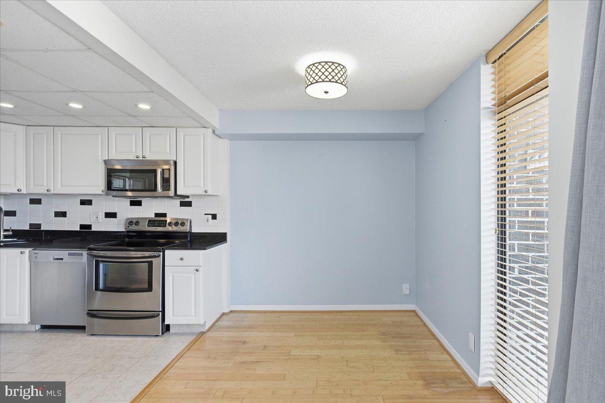 1401 North Rhodes Street, Unit 503 Arlington, VA 22209 - Photo 4 of 17 a kitchen with granite countertop white cabinets stainless steel appliances and sink