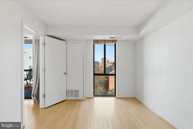 a view of an empty room with wooden floor and a window