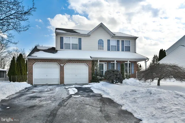 a front view of a house with a yard covered with snow in the road