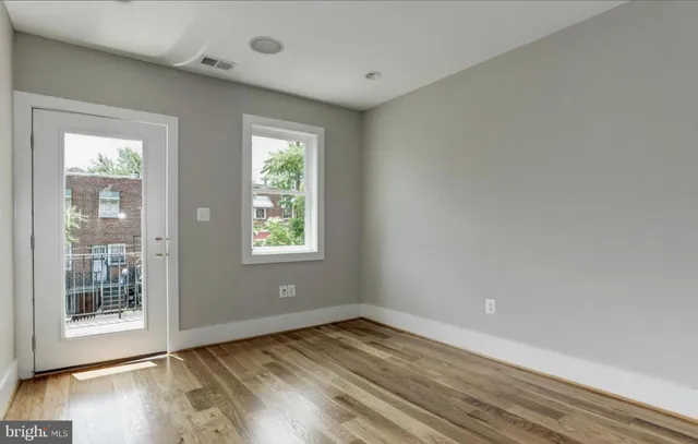 a view of an empty room with wooden floor and a window
