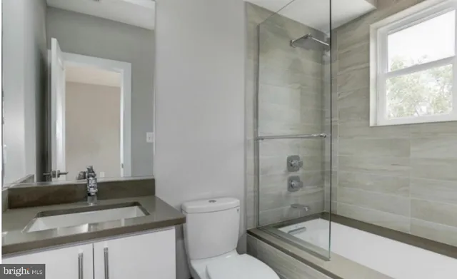 a bathroom with a granite countertop sink toilet a mirror and shower