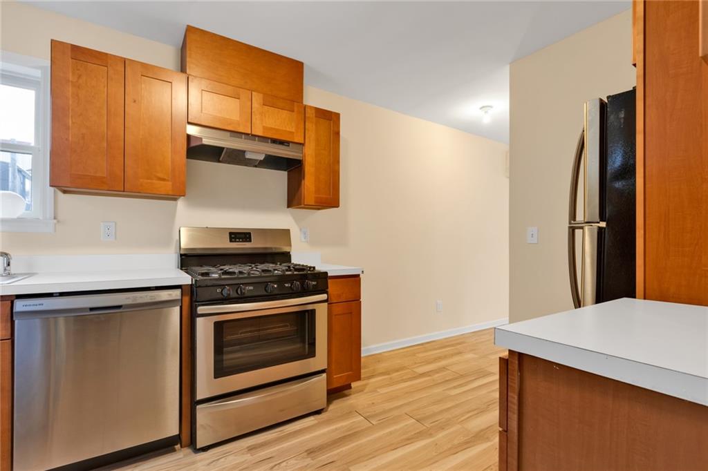 15 Stanton Road Brooklyn, NY 11235 - Photo 10 of 29 a kitchen with stainless steel appliances wooden floor sink and wooden cabinets