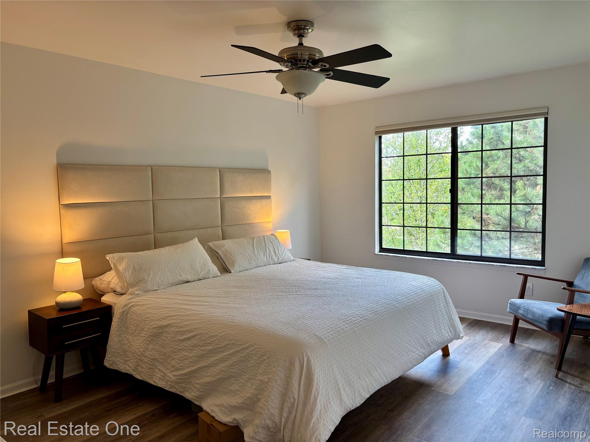 66 Meadow Wood Drive Rochester, MI 48307 - Photo 11 of 20 Spacious room featuring wood-finish flooring, a large window with black grid panes, and a ceiling fan with integrated lighting