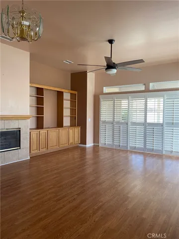 a view of an empty room with wooden floor fireplace and a window