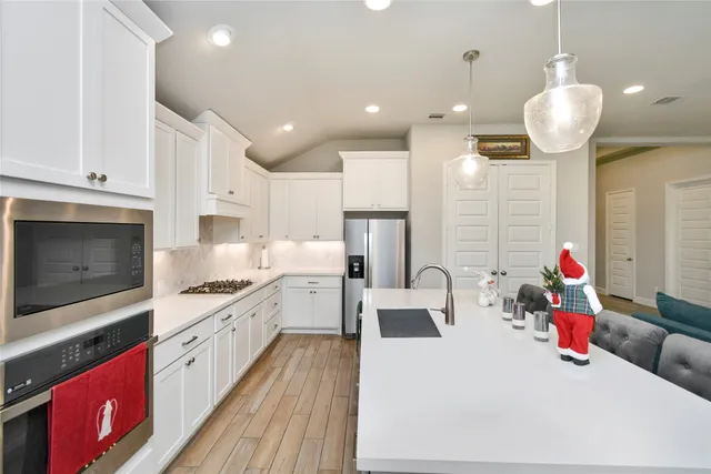 a large kitchen with stainless steel appliances kitchen island granite countertop a stove a sink and a microwave