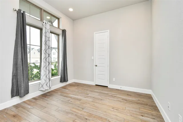 an empty room with wooden floor and windows