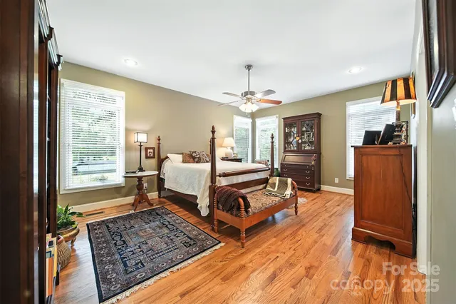a bedroom with wooden floor and large window