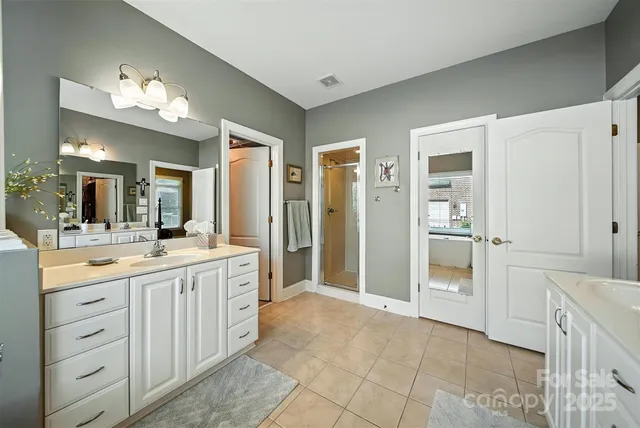 a spacious bathroom with a granite countertop sink a mirror and a shower