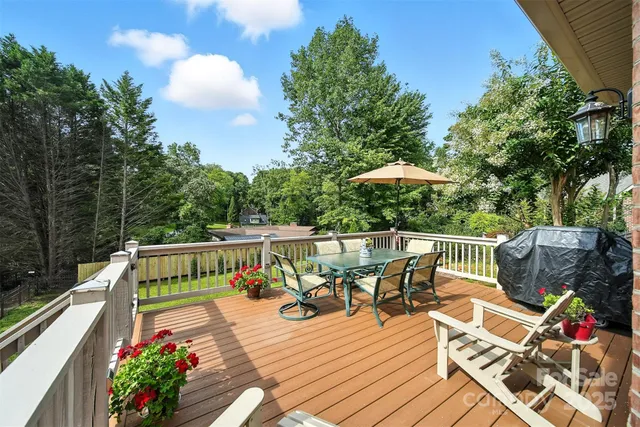 a view of a patio with couches table and chairs under an umbrella with wooden floor