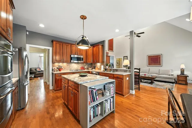 a kitchen with stainless steel appliances granite countertop a sink a stove and a wooden floors