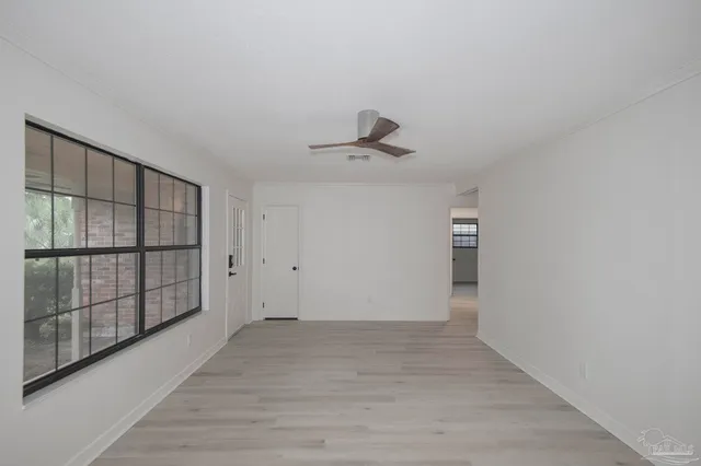a view of an empty room with wooden floor and a window