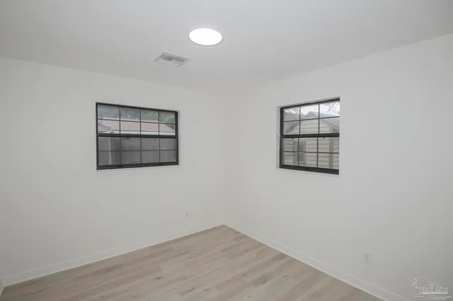a view of an empty room with a window and wooden floor