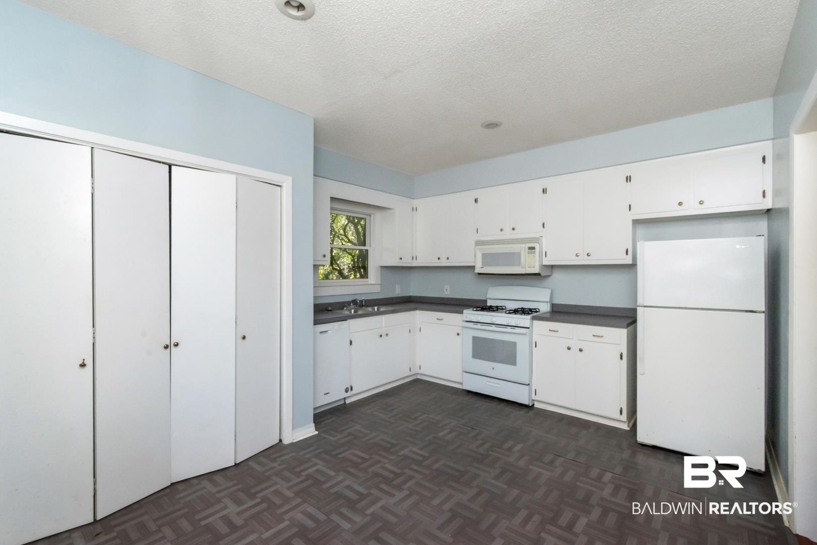 731 Jemison Street Mobile, AL 36606 - Photo 8 of 27 Kitchen with white appliances, dark countertops, white cabinetry, a textured ceiling, and parquet floors