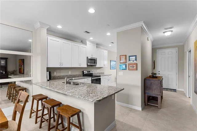 a kitchen with stainless steel appliances granite countertop table chairs stove refrigerator and cabinets