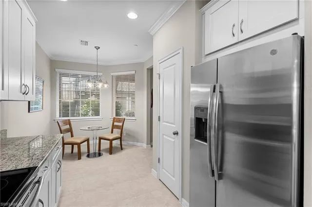 a dining room with stainless steel appliances granite countertop furniture and a chandelier