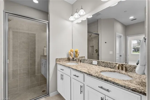 a bathroom with a granite countertop sink a mirror and a shower