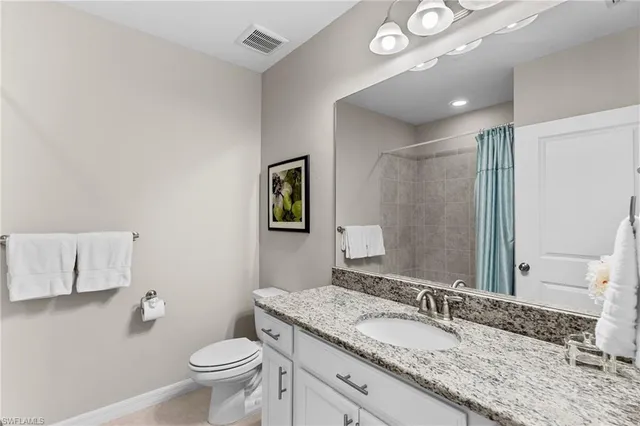 a bathroom with a granite countertop sink a toilet and a mirror
