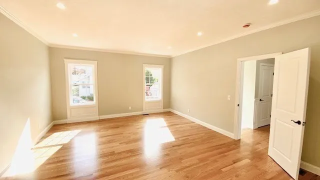 a view of an empty room with wooden floor and a window
