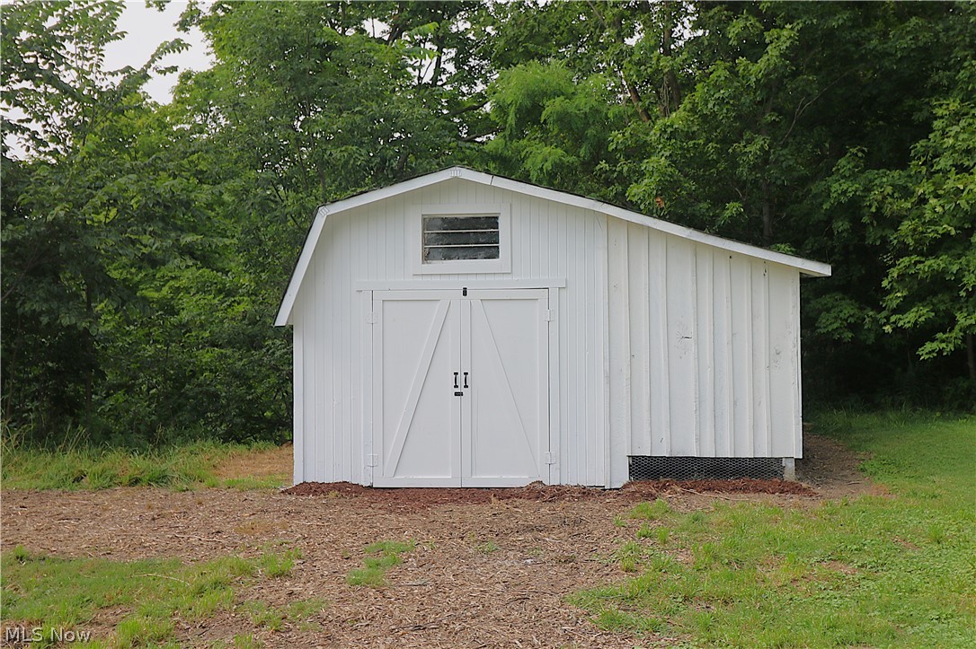 5236 Zenobia Road Wakeman, OH 44889 - Photo 28 of 31 White gambrel-style chicken coop featuring double barn doors, a transom window, and vertical board siding