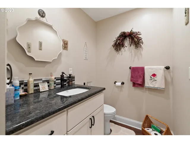 a bathroom with a granite countertop sink a toilet and a mirror