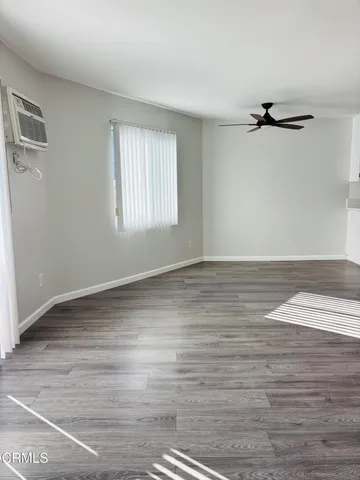 an empty room with wooden floor window and a ceiling fan