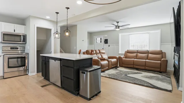 a living room with stainless steel appliances granite countertop furniture a fireplace a flat screen tv and a window