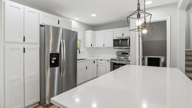 a kitchen with refrigerator a microwave a stove and white cabinets