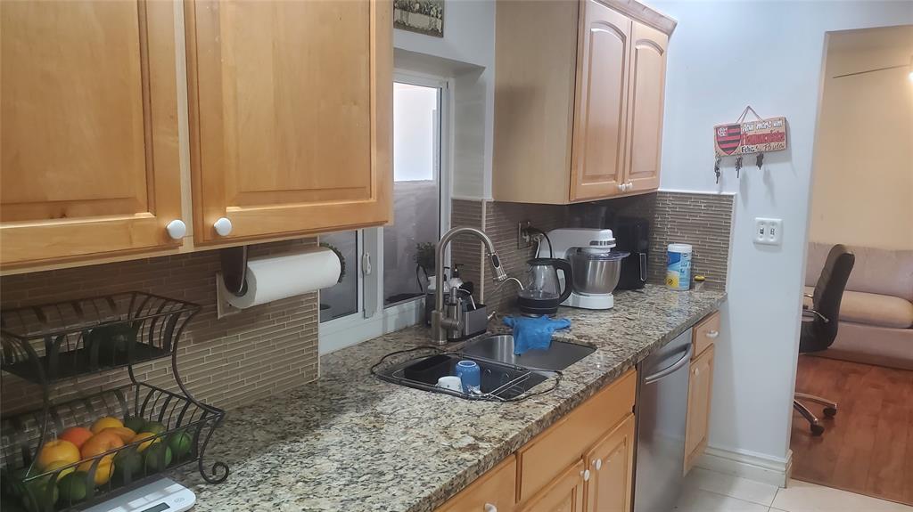 616 Southeast 8th Avenue Deerfield Beach, FL 33441 - Photo 11 of 38 a kitchen with granite countertop a sink a stove and a wooden cabinets