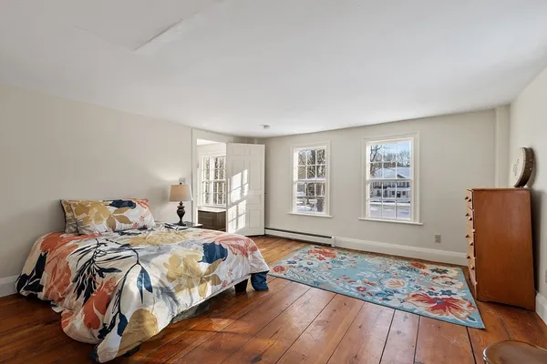 a bedroom with a bed and a chair with the wooden floor